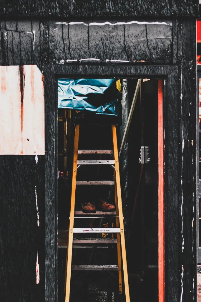 photography of person on A-frame ladder near door