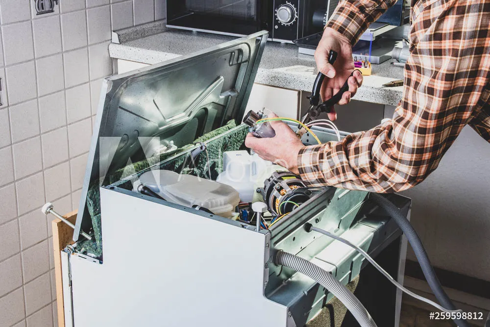 People in technician jobs. Appliance repair technician or handyman works on broken dishwasher in a kittchen. Laborer is changing the heating element.