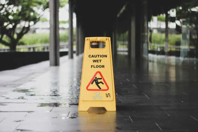 yellow Caution wet floor signage on wet pavement