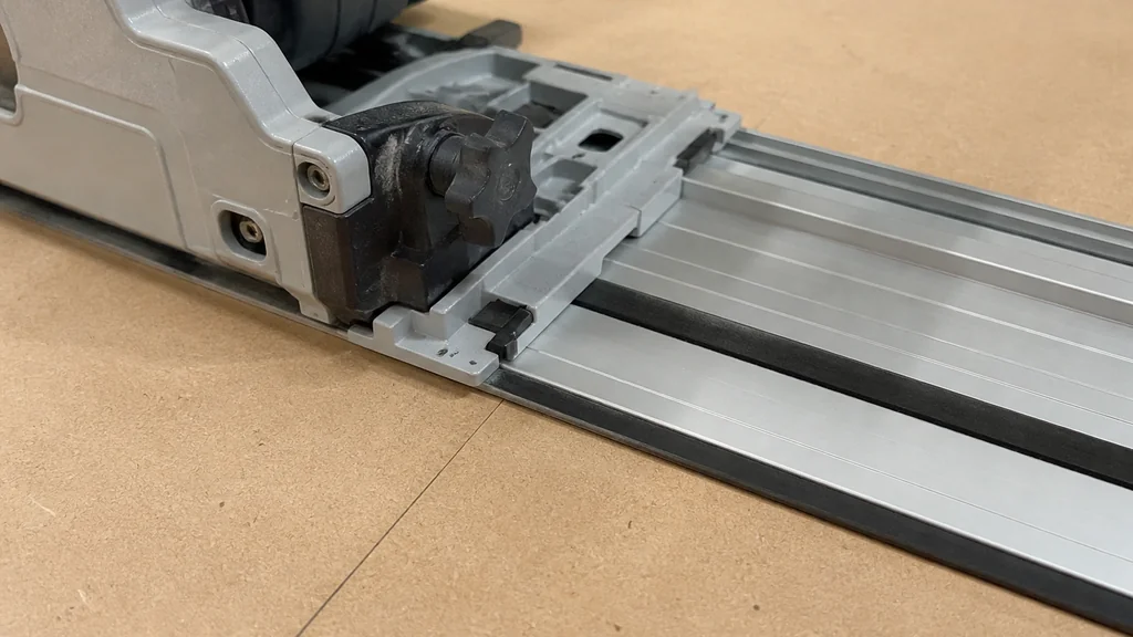 Track saw base aligned on guide rail over pencil line